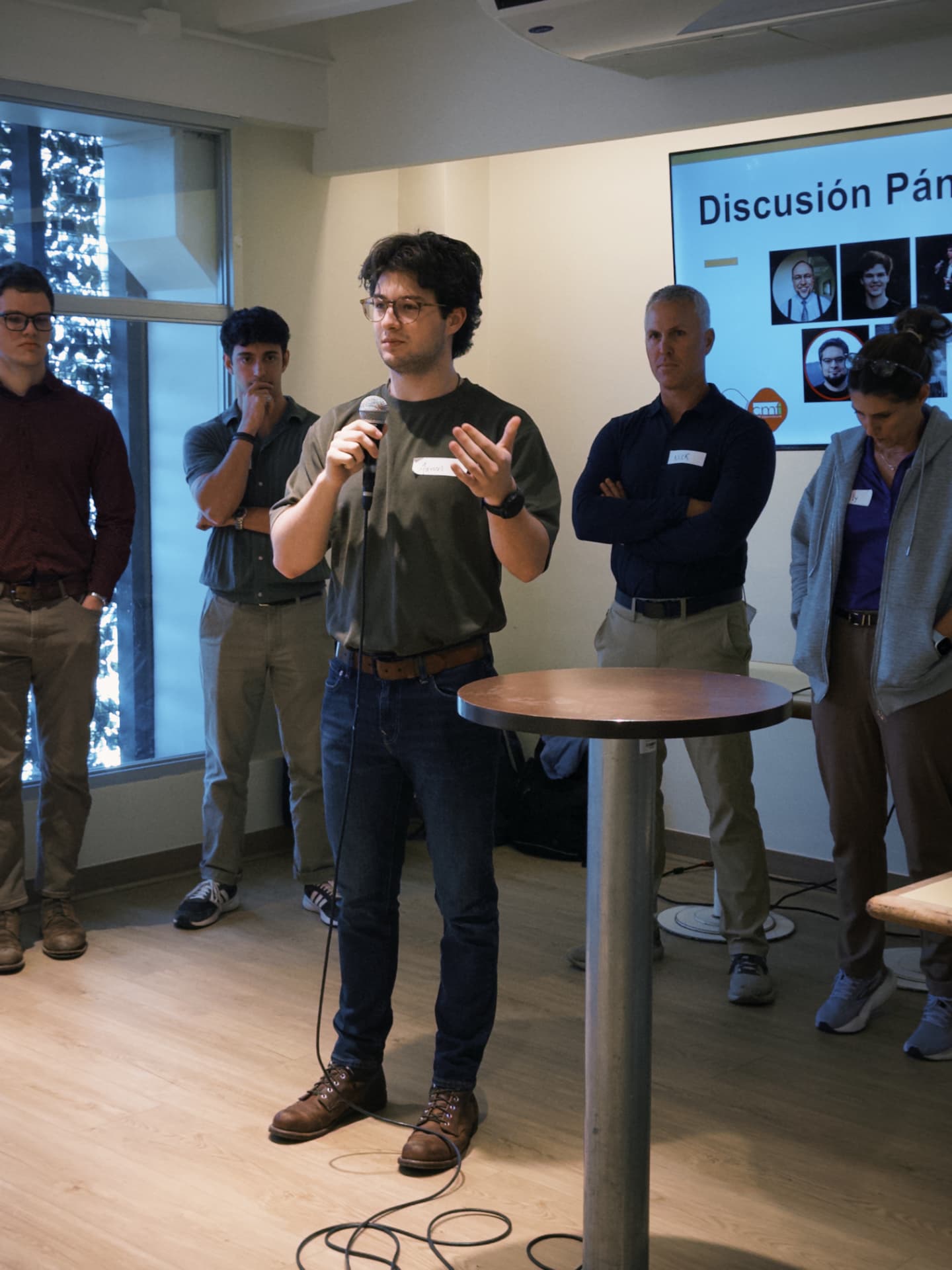 A fellow in a green polo pitching into a microphone at a house event
